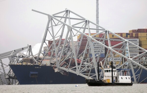 A cargo ship is stuck under the part of the structure of the Francis Scott Key Bridge after the ship hit the bridge Wednesday, March 27, 2024, in Baltimore, Md. (AP Photo/Steve Helber)