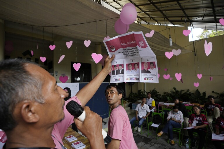 An electoral worker shows a ballot paper during the vote counting for the presidential and legislative election at a Valentine's Day-themed polling station in Solo, Central Java, Indonesia, Wednesday, Feb. 14, 2024. (AP Photo/Achmad Ibrahim)