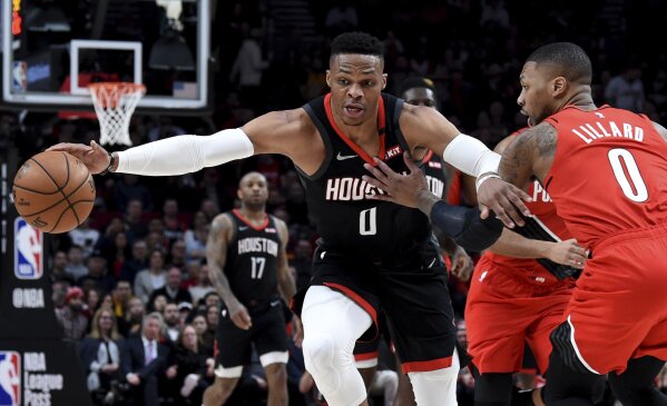 FILE - In this Jan. 29, 2020, file photo, Houston Rockets guard Russell Westbrook, left, dribbles next to Portland Trail Blazers guard Damian Lillard, right, during the first half of an NBA basketball game in Portland, Ore. Westbrook said Monday, July 13, 2020, that he has tested positive for coronavirus, and that he plans to eventually join his team at the restart of the NBA season. Westbrook made the revelation on social media. As recently as Sunday, the Rockets believed that Westbrook and James Harden — neither of whom traveled with the team to Walt Disney World near Orlando last week — would be with the team in the next few days. In Westbrook's case, that now seems most unlikely. (AP Photo/Steve Dykes, File)