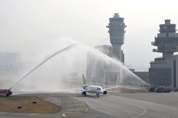 In this photo taken Dec. 12, 2023 and released by Hong Kong Government Information Services, the Chinese-made C919, is welcomed upon arrival at the Hong Kong International Airport. The Chinese C919 commercial passenger jet has arrived in Hong Kong in the Chinese-made aircraft's first foray outside of mainland China. The C919 plane and another Chinese-made aircraft, an ARJ21, landed Tuesday and will be on display at Hong Kong's international airport until Sunday. (Hong Kong Government Information Services via AP)