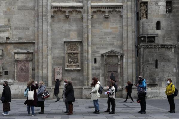 People line up for vaccination in front of the St. Stephen's Cathedral in Vienna, Austria, Friday, Nov. 19, 2021. Austrian Chancellor Alexander Schallenberg says the country will go into a national lockdown to contain a fourth wave of coronavirus cases. Schallenberg said the lockdown will start Monday, Nov.22 and initially last for 10 days. (AP Photo/Lisa Leutner)