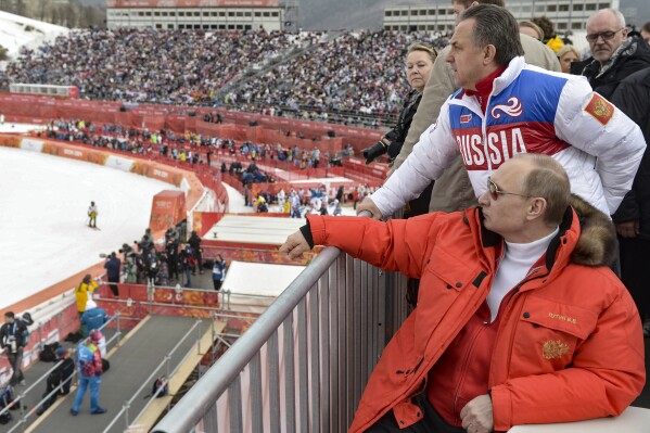 FILE - Russian President Vladimir Putin, foreground, watches downhill ski competition of the 2014 Winter Paralympics in Roza Khutor mountain district near Sochi, Russia, as Sports Minister Vitaly Mutko stands behind him on March 8, 2014. (Alexei Nikolsky, Sputnik, Kremlin Pool Photo via AP, File)