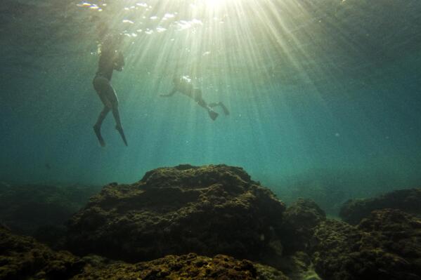 People snorkel in the Mediterranean Sea in Gador sea reserve, in Hadera, northern Israel, Saturday, Oct. 29, 2022. Climate change, invasive species and explosive human activity are threatening what remains of the eastern Mediterranean's severely impacted ecosystems. (AP Photo/Ariel Schalit)