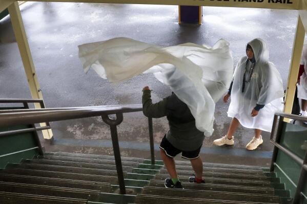 A gust of window blows a guest's rain poncho on the ferry boat on the way to the Magic Kingdom at Walt Disney World in Lake Buena Vista, Fla., Wednesday, Nov. 9, 2022, as conditions deteriorate with the approach of Hurricane Nicole. All 4 Disney parks in Central Florida closed early Wednesday because of the impending storm. (Joe Burbank/Orlando Sentinel via AP)