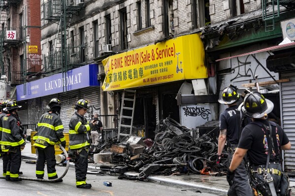 Firefighters and investigators go through the aftermath of a fire which authorities say started at an e-bike shop and spread to upper-floor apartments, Tuesday, June 20, 2023, in New York. (AP Photo/Bebeto Matthews)