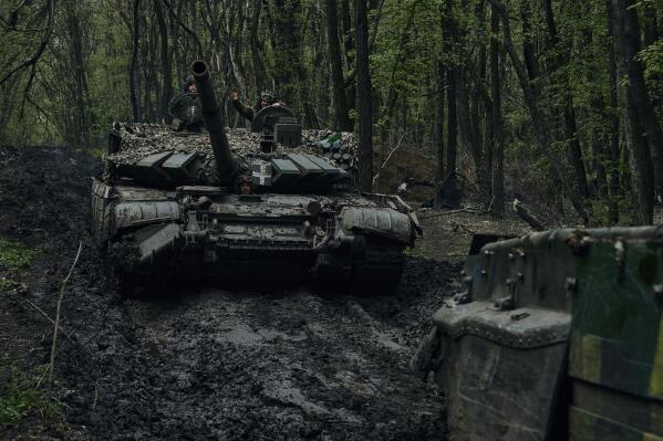 Ukrainian soldiers wave atop a passing tank on the frontline in Bakhmut, Donetsk region, Ukraine, Sunday, April 23, 2023. (AP Photo/Libkos)