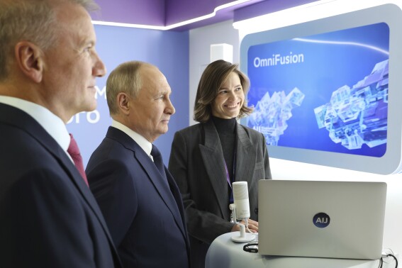 Russian President Vladimir Putin, center, and Sberbank CEO German Gref, left, visit an exhibition on artificial intelligence in Moscow, Russia, Friday, Nov. 24, 2023. Putin takes part in the plenary session of the international conference on artificial intelligence and machine learning "Artificial Intelligence Journey 2023" on the topic "The Generative AI Revolution: New Opportunities." (Mikhail Klimentyev, Sputnik, Kremlin Pool Photo via AP)
