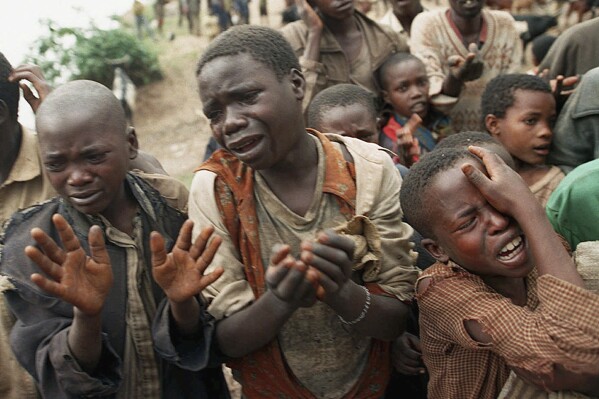 FILE - Rwandan refugee children plead with Zairean soldiers to allow them across a bridge separating Rwanda and Zaire, which is now the Democratic Republic of Congo, where their mothers had crossed moments earlier before the soldiers closed the border, Aug. 20, 1994. Appeals judges on Monday, Aug. 7, 2023 threw out a decision by a United Nations court to set up a procedure to hear evidence against an elderly Rwandan genocide suspect who was declared unfit to face trial. (AP Photo/Jean-Marc Bouju, file)