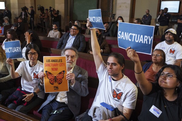 Members of immigration advocacy groups react as Los Angeles City Council votes to enact an ordinance to prohibit city resources from being used for immigration enforcement in anticipation of potential mass deportations under President-elect Donald Trump, inside Los Angeles City Hall on Tuesday, Nov. 19, 2024. (AP Photo/Damian Dovarganes, File)