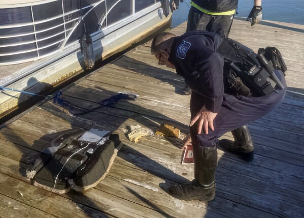 This image provided by Dean Naujoks shows a law enforcement officer looking at debris recovered from the Potomac River on a dock on Daingerfield Island south of Ronald Reagan Washington National Airport in Alexandria, Va., Thursday, Jan. 30, 2025 (Dean Naujoks via AP)