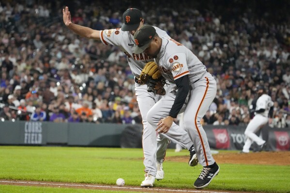 San Francisco Giants relief pitcher Tyler Rogers, left, and first baseman LaMonte Wade Jr., right, wait for the ball bit by Colorado Rockies' Ezequiel Tovar to roll foul in the seventh inning of the second baseball game of a doubleheader, Saturday, Sept. 16, 2023, in Denver. (AP Photo/Jack Dempsey)