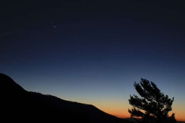 In this Sunday, Dec. 13, 2020 photo made available by NASA, Saturn, top, and Jupiter, below, are seen after sunset from Shenandoah National Park in Luray, Va. The two planets are drawing closer to each other in the sky as they head towards a "great conjunction" on Monday, Dec. 21, where the two giant planets will appear a tenth of a degree apart. (Bill Ingalls/NASA via AP)