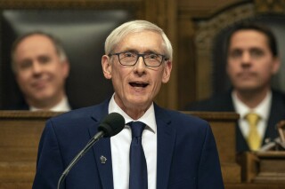 Wisconsin Gov. Tony Evers, with Assembly Speaker Robin Vos, left, and Senate President Roger Roth behind him, addresses a joint session of the Legislature in the Assembly chambers during the Governor's State of the State speech at the state Capitol, Tuesday, Jan. 22, 2019, in Madison, Wis. Democratic Gov. Tony Evers' administration and political opponent Republican Assembly Speaker Robin Vos are in the extremely rare position of taking the same side in a lawsuit seeking to immediately end Wisconsin's taxpayer-funded voucher school system, telling the Wisconsin Supreme Court that it should not take the case. (AP Photo/Andy Manis, File)