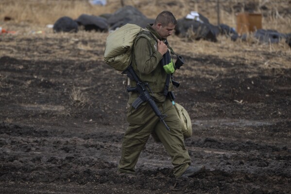 An Israeli soldier walks during a rainfall near the Israeli border with Lebanon, on Sunday, Oct. 15, 2023. (AP Photo/Petros Giannakouris)