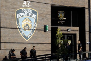 FILE - Police officers stand in front of the 47th precinct in the Bronx borough of New York, Sunday, Sept. 29, 2019. New York City has agreed to pay $17.5 million to settle a lawsuit filed by two Muslim women who were forced to remove their head coverings to be photographed after they were arrested. The settlement was filed Friday, April 5, 2024, and requires approval by a federal judge. (AP Photo/Seth Wenig, File)