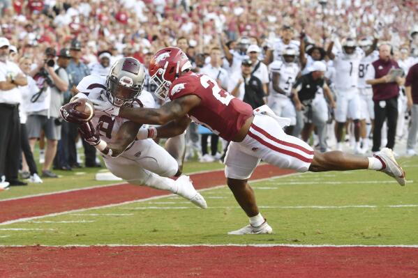 Missouri State running back Jacardia Wright, left, dives past Arkansas linebacker Chris Paul Jr., right, to score a touchdown during the first half of an NCAA college football game Saturday, Sept. 17, 2022, in Fayetteville, Ark. (AP Photo/Michael Woods)