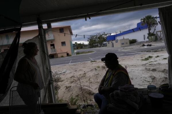 Jacquelyn, left, and Timothy Velazquez spend time on the back porch of their home, which flooded to within inches of the ceiling during Hurricane Ian's passage last September, in Fort Myers Beach, Fla., Wednesday, May 24, 2023. Ian claimed more than 156 lives in the U.S., the vast majority in Florida, according to a comprehensive NOAA report on the hurricane. In hard-hit Lee County, location of Fort Myers Beach and the other seaside towns, 36 people died from drowning in storm surge and more than 52,000 structures suffered damage, including more than 19,000 destroyed or severely damaged, a NOAA report found. (AP Photo/Rebecca Blackwell)