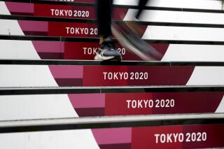 A commuter walks down stairs leading to a subway station before the start of the 2020 Summer Olympics, Wednesday, July 21, 2021, in Tokyo. (AP Photo/Jeff Roberson)