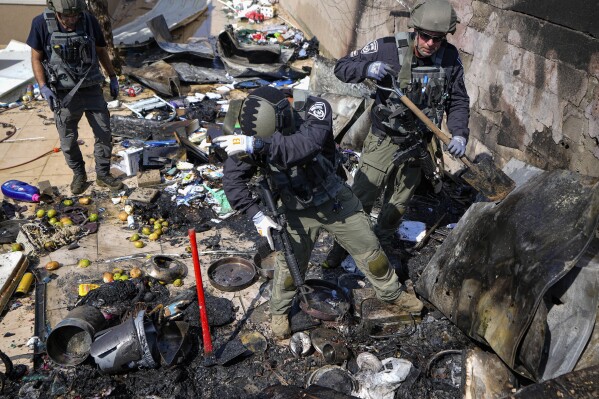 Israeli police extinguish a fire at a site struck by a rocket from the Gaza Strip, in the town of Sderot, southern Israel, Sunday, Oct. 15, 2023. (AP Photo/Ariel Schalit)