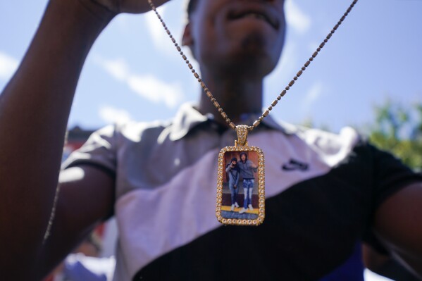 Jah Johnson holds a necklace displaying a picture of him and Antonio Lee following a funeral service for Lee, Thursday, Aug. 31, 2023, in Baltimore. Lee, 19, a squeegee worker was killed during a shooting as he panhandled in a Baltimore street corner. (AP Photo/Julio Cortez)