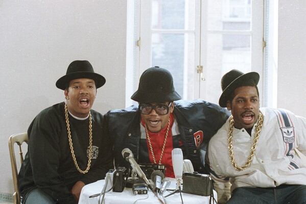 FILE - Rap group RUN D.M.C., in London for two concerts, talk during a news conference. The group, left to right, is Joseph Simmons, Darryl McDaniels, and Jason Mizell. The signs of hip-hop’s influence are everywhere — but it didn't start out that way. Even though the company had seen an unusual spike in sales of its Superstar shoes in the Northeast in 1986, it wasn't ready to attribute that to Run-D.M.C. and their hit “My Adidas.” When company execs saw the group ask fans to show off their Adidas and thousands removed their shoes and waved them in the air at a Madison Square Garden performance, they were sold. They signed the rap group to a $1 million deal that resulted in their own shoe line in 1988. (AP Photo/Peter Kemp, file)