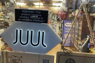 FILE - A Juul sign hangs in the front window of a bodega convenience store in New York City on June 25, 2022. Vaping company Juul Labs will pay Chicago $23.8 million to settle a lawsuit alleging the company marketed harmful vaping products to underage users, the city announced Friday, March 10, 2023. (AP Photo/Ted Shaffrey, File)