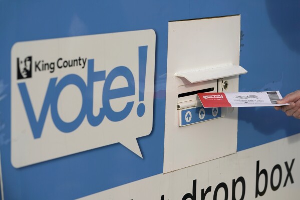 FILE - A person puts their ballot in a drop box on Oct. 27, 2020, at a library in Seattle. A Washington state judge on Friday, June 7, 2024, turned back an attempt by GOP backers of three initiatives to keep the fiscal impact of the measures off the November ballot. (AP Photo/Ted S. Warren, File)