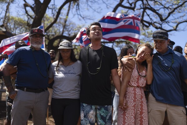 Community organizer Tiare Lawrence, second from right, is comforted by Archie Kalepa as they sing a song during a news conference with Lahaina, Hawaii, residents affected by a deadly wildfire in Lahaina, Hawaii, Aug. 18, 2023. (AP Photo/Jae C. Hong)