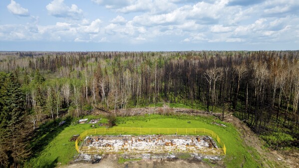 Yellow fencing surrounds a fourplex destroyed by a May wildfire at Sturgeon Lake Cree First Nation, northwest of Edmonton, Alberta, on Tuesday, July 3, 2023. The building housed four of the tribe's elders. (AP Photo/Noah Berger)