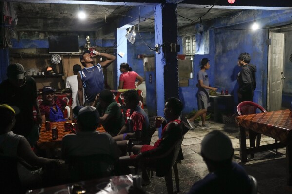 Patrons gather at a bar in Gardi Sugdub Island, part of the San Blas archipelago off Panama's Caribbean coast, Saturday, May 25, 2024. Due to rising sea levels, about 300 Guna Indigenous families will relocate to new homes, built by the government, on the mainland. (AP Photo/Matias Delacroix)