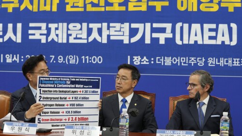 Main opposition Democratic Party lawmaker Woo Won-shik, left, shows a list of proposed disposal methods for the Fukushima contaminated water as his party lawmaker Wi Seong-gon and Rafael Mariano Grossi, Director General of the International Atomic Energy Agency, right, look on during a meeting with the party's lawmakers at the National Assembly in Seoul, South Korea, Sunday, July 9, 2023. (AP Photo/Ahn Young-joon)