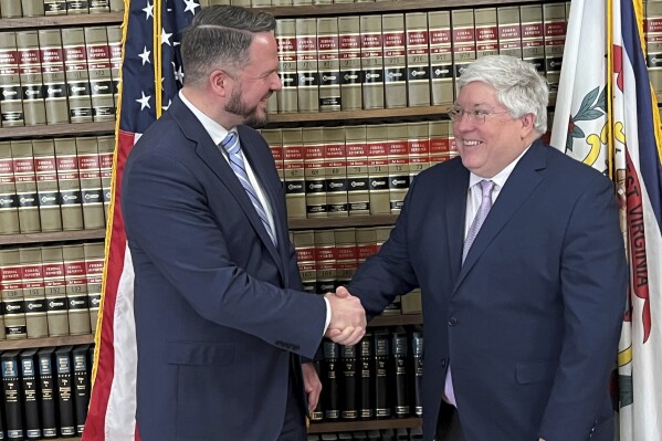 In this photo provided by the West Virginia Attorney General's Office, Jonathan Board, left, and West Virginia Attorney General Patrick Morrisey shake hands after Board was announced as the West Virginia First Foundation executive director Thursday, March 14, 2024, in Morrisey's office at the state Capitol in Charleston, W.Va. The foundation will be distributing the majority of the state's more than $1 billion in opioid settlements. (Aimee Cantrell/West Virginia Attorney General's Office via AP)