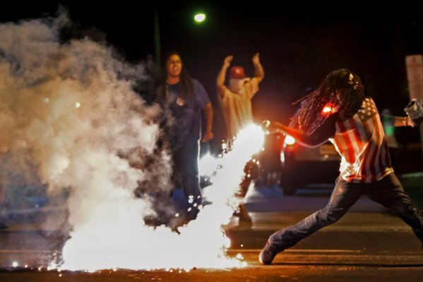 FILE - Edward Crawford Jr. returns a tear gas canister fired by police trying to disperse a protest against the shooting of Michael Brown in Ferguson, Mo., on Aug. 13, 2014. (Robert Cohen/St. Louis Post-Dispatch via AP, File)