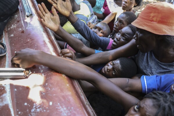 People displaced by armed attacks receive food from a nongovernmental organization in Saint-Marc, Haiti, Sunday, Oct. 6, 2024. (AP Photo/Odelyn Joseph)