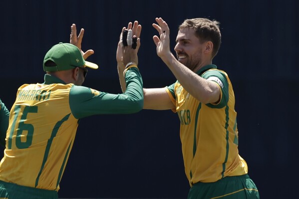 South Africa's Anrich Nortje, right, celebrates with teammate Keshav Maharaj after the dismissal of Sri Lanka's Charith Asalanka during the ICC Men's T20 World Cup cricket match between South Africa and Sri Lanka at the Nassau County International Cricket Stadium in Westbury, New York, Monday, June 3, 2024. (AP Photo/Adam Hunger)