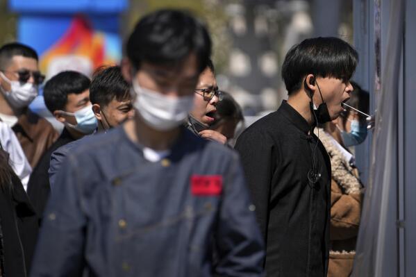 Workers wearing face masks to help protect from the coronavirus line up to get their throat swab at a coronavirus testing site, Sunday, April 3, 2022, in Beijing. COVID-19 cases in China's largest city of Shanghai are still rising as millions remain isolated at home under a sweeping lockdown. (AP Photo/Andy Wong)