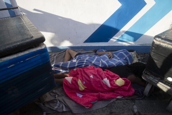 Beverage vendors sleep on a sidewalk before the start of the Heaven on Earth pre-Carnival street party, in Rio de Janeiro, Saturday, Feb. 22, 2025. (AP Photo/Bruna Prado)