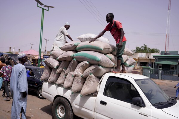 FILE - Workers offload bags of grains from a truck at a market in Gombe, Nigeria, on June 3, 2024. The World Bank has approved a $2.25 billion loan for Nigeria to shore up revenue and support economic reforms that have contributed to the worst cost-of-living crisis in many years for Africa’s most populous country. (AP Photo/Sunday Alamba, File)