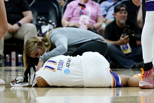CORRECTS TO SHEY PEDDY NOT SUG SUTTON - Phoenix Mercury guard Shey Peddy, bottom, is looked at by Mercury team training staff after being fouled during the first half of a WNBA basketball game against the Seattle Storm, Saturday, Aug. 5, 2023, in Phoenix. (AP Photo/Ross D. Franklin)