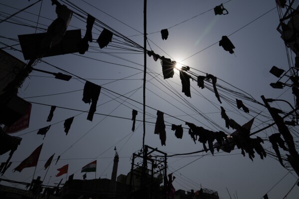 Clothes thrown by revelers hang from overhanging cables as they dance during celebrations to mark Holi, the Hindu festival of colors at loknath Prayagraj, northern Uttar Pradesh state, India, Monday March 25, 2024. (AP Photo/Rajesh Kumar Singh)