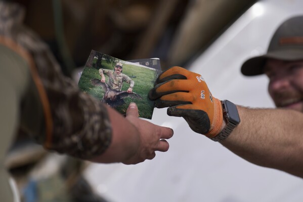 Family friend Melvin Brock on the right finds photos in London, Kentucky on Sunday, May 18, 2025, after a violent storm passed through the area. (AP Photo/Caroline Custer)