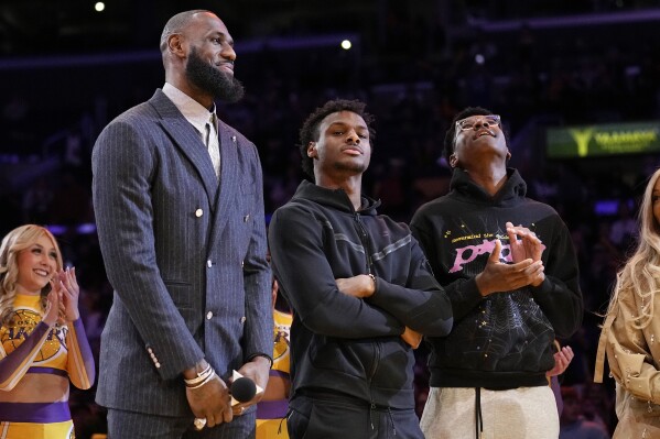 FILE - Los Angeles Lakers forward LeBron James, second from left, Bronny James, center, and Bryce James stand during a ceremony honoring LeBron James as the NBA's all-time leading scorer, before the Lakers' basketball game against the Milwaukee Bucks on Feb. 9, 2023, in Los Angeles. Bronny James was hospitalized in stable condition Tuesday, July 25, 2023, a day after going into cardiac arrest while participating in a practice at the University of Southern California, a family spokesman said. (AP Photo/Mark J. Terrill)