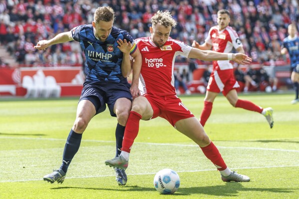 Heidenheim's Patrick Mainka, left, and Berlin's Benedict Hollerbach, right, challenge for the ball during the German Bundesliga soccer match between 1. FC Union Berlin and FC Heidenheim in Berlin, Germany, Saturday, May 10, 2025. (Andreas Gora/dpa via AP)
