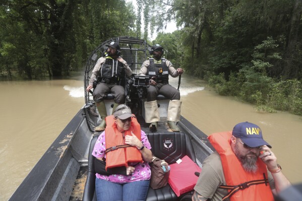 Les gardes-chasse du Texas Parks and Wildlife Department utilisent un bateau pour sauver les résidents des eaux de crue dans le comté de Liberty, Texas, le samedi 4 mai 2024.  (Photo AP/Lekan Oyekanmi)