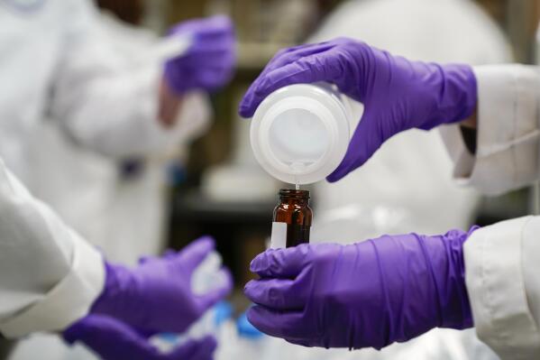 FILE - Eva Stebel, water researcher, pours a water sample into a smaller glass container for experimentation as part of drinking water and PFAS research at the U.S. Environmental Protection Agency Center For Environmental Solutions and Emergency Response on Feb. 16, 2023, in Cincinnati. Three chemical companies said Friday, June 2, 2023, that they had reached a $1.18 billion deal to resolve complaints of polluting many U.S. drinking water systems with potentially harmful compounds known as PFAS. (AP Photo/Joshua A. Bickel, File)