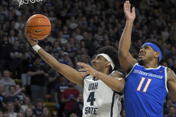 Utah State guard Ian Martinez (4) drives to the basket as Boise State guard Chibuzo Agbo (11) defends during the first half of an NCAA college basketball game Saturday, Feb. 10, 2024, in Logan, Utah. (Eli Lucero/The Herald Journal via AP)