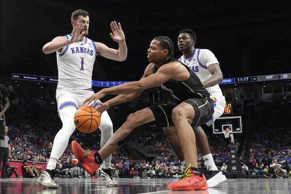 UCF's Keyshawn Hall (4) chases a loose ball as Kansas' Hunter Dickinson (1) and Flory Bidunga, right, defend during the first half of an NCAA college basketball game in the second round of the Big 12 Conference tournament, Wednesday, March 12, 2025, in Kansas City, Mo. (AP Photo/Charlie Riedel)