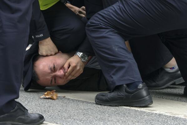 In this photo taken on Sunday, Nov. 27, 2022, policemen pin down and arrest a protester during a protest on a street in Shanghai, China. Authorities eased anti-virus rules in scattered areas but affirmed China's severe "zero- COVID" strategy Monday after crowds demanded President Xi Jinping resign during protests against controls that confine millions of people to their homes. (AP Photo)