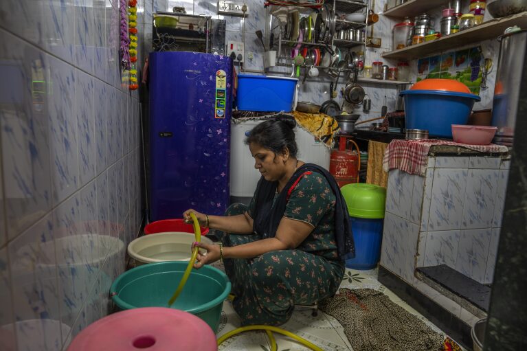 Aarti Sandeep Kawade fills buckets and pans with water for cooking and washing clothes and dishes inside her dwelling in Dharavi, one of Asia's largest slums, in Mumbai, India, Wednesday, May 3, 2023. (AP Photo/Dar Yasin)