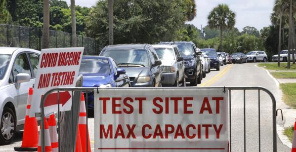 Signage stands at the ready (foreground) in case COVID-19 testing at Barnett Park reaches capacity, as cars wait in line in Orlando, Fla., Thursday, July 29, 2021. The line stretched through the park for more than a mile out to West Colonial Drive near the Central Florida Fairgrounds. Orange County is under a state of emergency as coronavirus infections skyrocket in Central Florida. The Barnett Park site is testing 1,000 people a day and has closed early in recent days due capacity limits. (Joe Burbank/Orlando Sentinel via AP)
